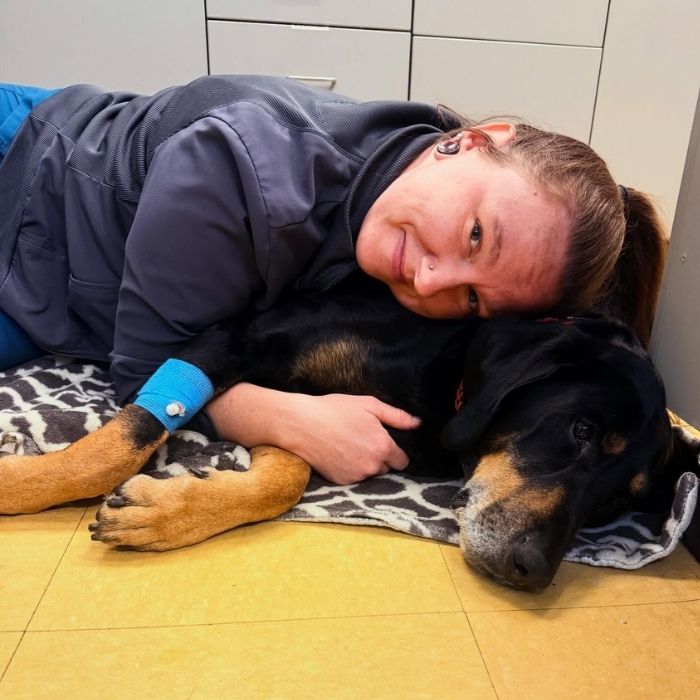 Smiling woman cuddles a black-and-tan dog